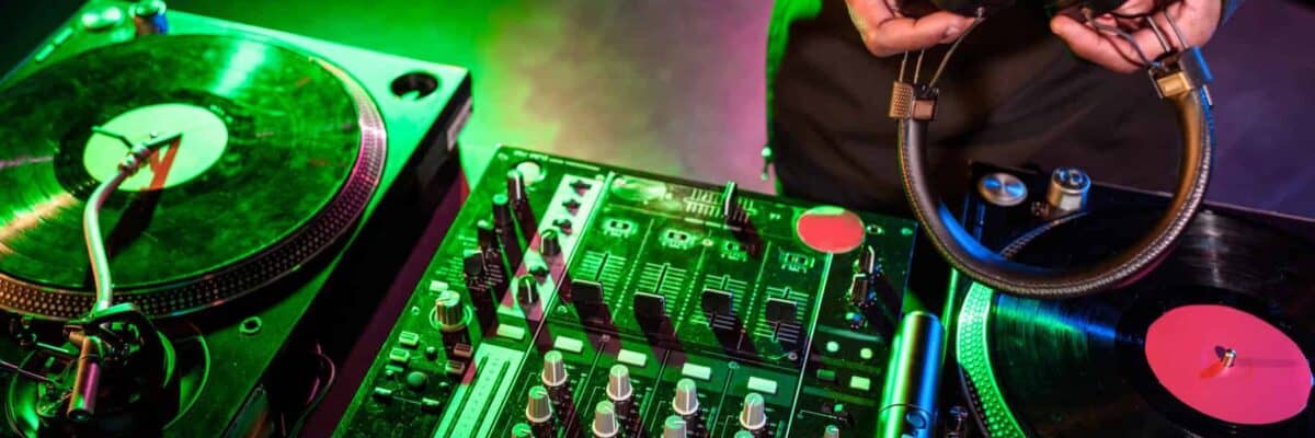 cropped view of club DJ hands holding headphones over sound mixer