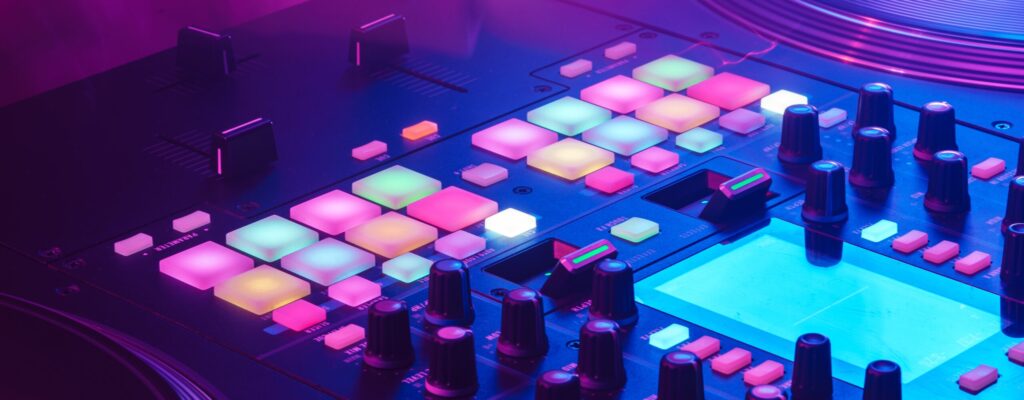 Close up photo of DJ mixing console in party light